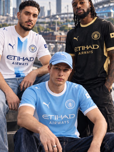 Collection Manchester City 2026/27 avec trois modèles portant les maillots bleu ciel, noir et blanc à rayures bleues.