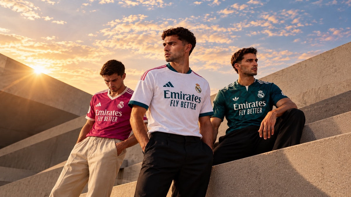 Trois modèles portant les maillots officiels du Real Madrid 2026/27 : domicile blanc, extérieur rose et third vert foncé, avec sponsor Emirates.
